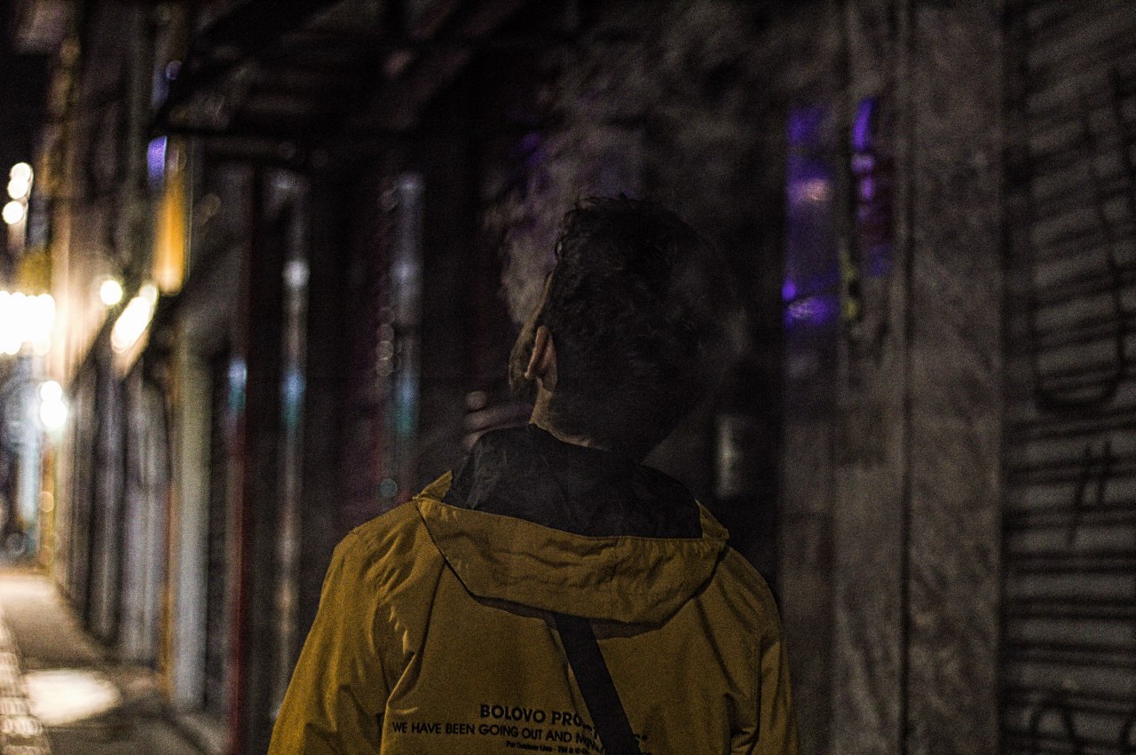 An picture of me from behind, I'm walking in a dark city night with a yellow jacket.